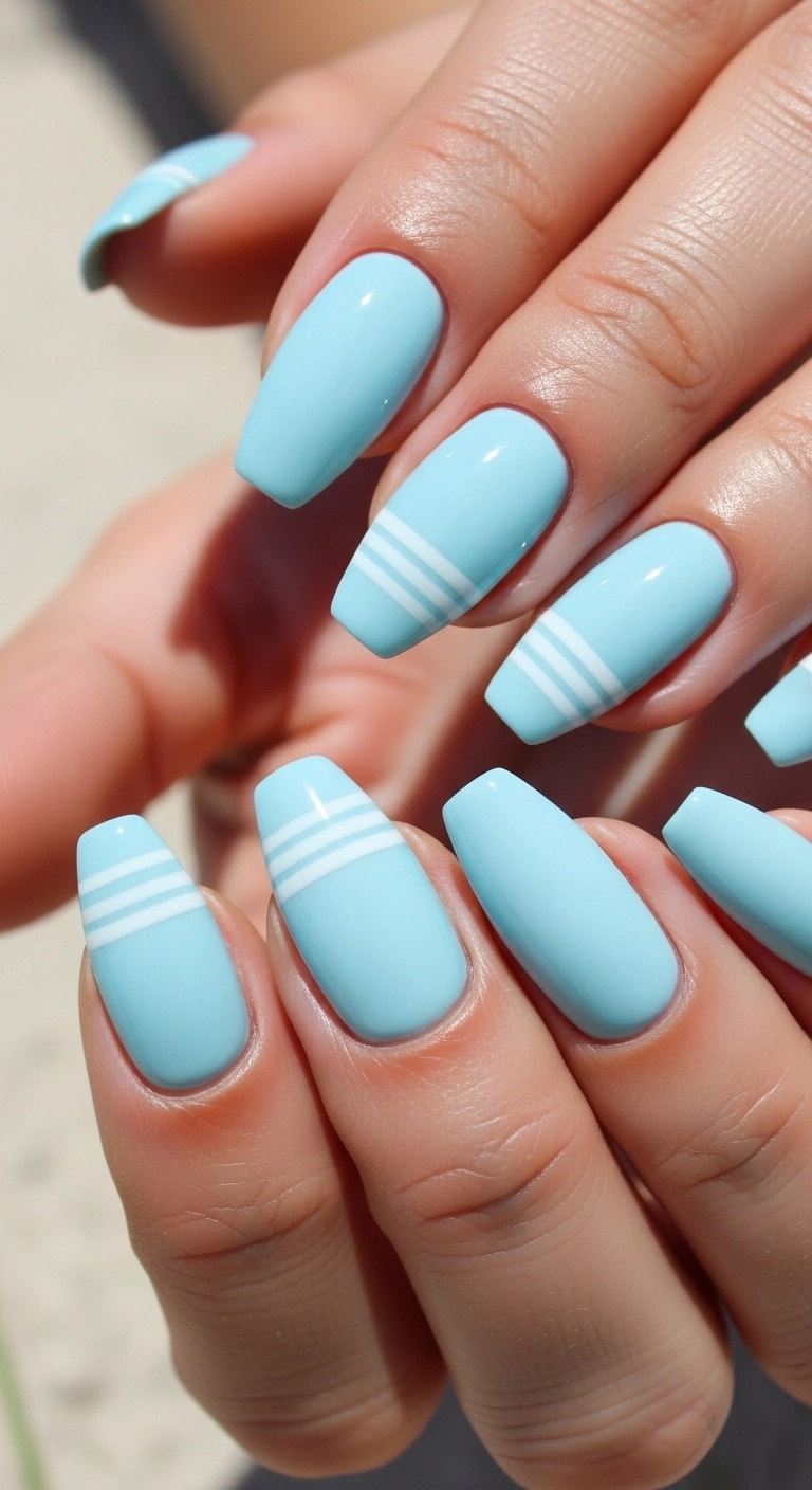 Hand with pastel blue summer nails and white stripes.
